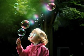 小孩吹泡泡玩耍绿叶背景