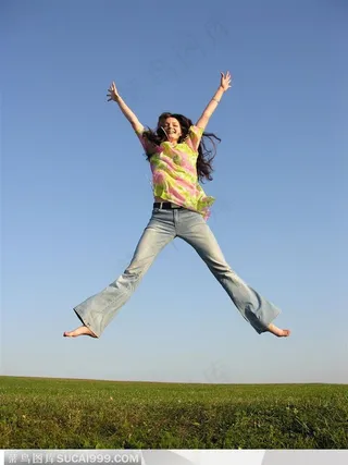 穿牛仔裤的外国女孩双手双脚张开再草地上跳跃