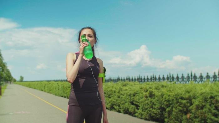 跑步后穿运动服喝水的女人