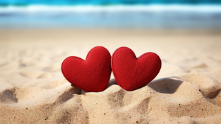 海边沙滩上摆放着两个红色爱心互相依靠摄影图