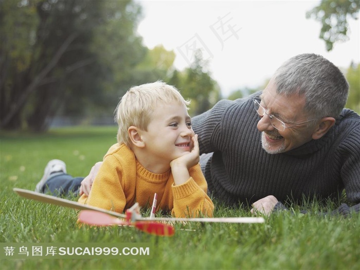 户外草坪上祖孙趴在地上玩耍特写