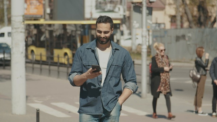 充满希望的男人在穿过城市时对社交媒体微笑