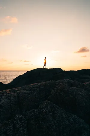 站在岩石山面对大海的人