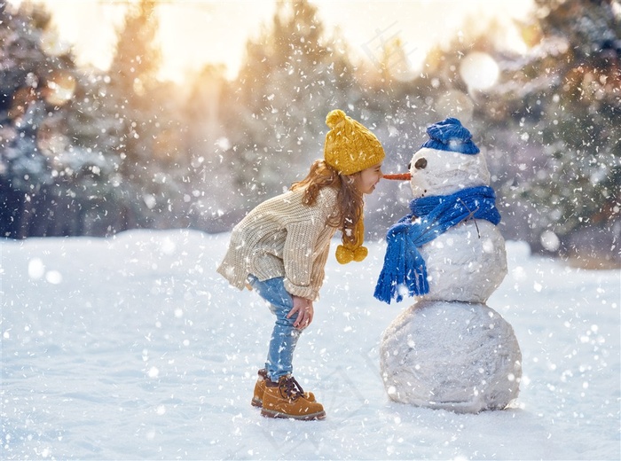 在雪地里和雪人玩耍的小女孩高清图片