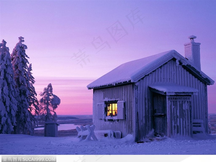 夕阳下被雪覆盖的小木屋雪景