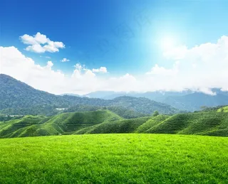 蓝天下的绿草地和起伏的山脉高清图片