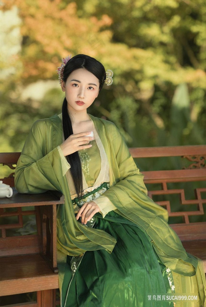 坐在庭院休憩长椅上喝茶的古装绿服女子图片