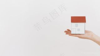 特写手拿着迷你房子模型白色背景