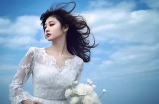 一个美女穿着一件漂亮的白色连衣裙在海边的拍照摄影图