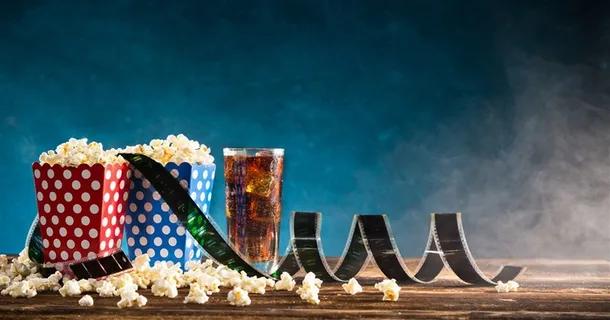 蓝色背景上散落的爆米花和电影底片高清图片