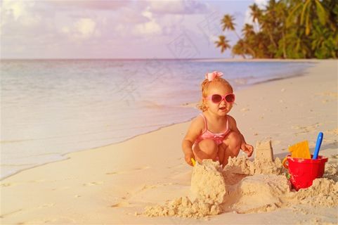 海边开心玩着沙子的小女孩
