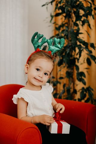 圣诞节室内圣诞装饰的小公主俏皮地歪头看镜头准备打开礼物场景