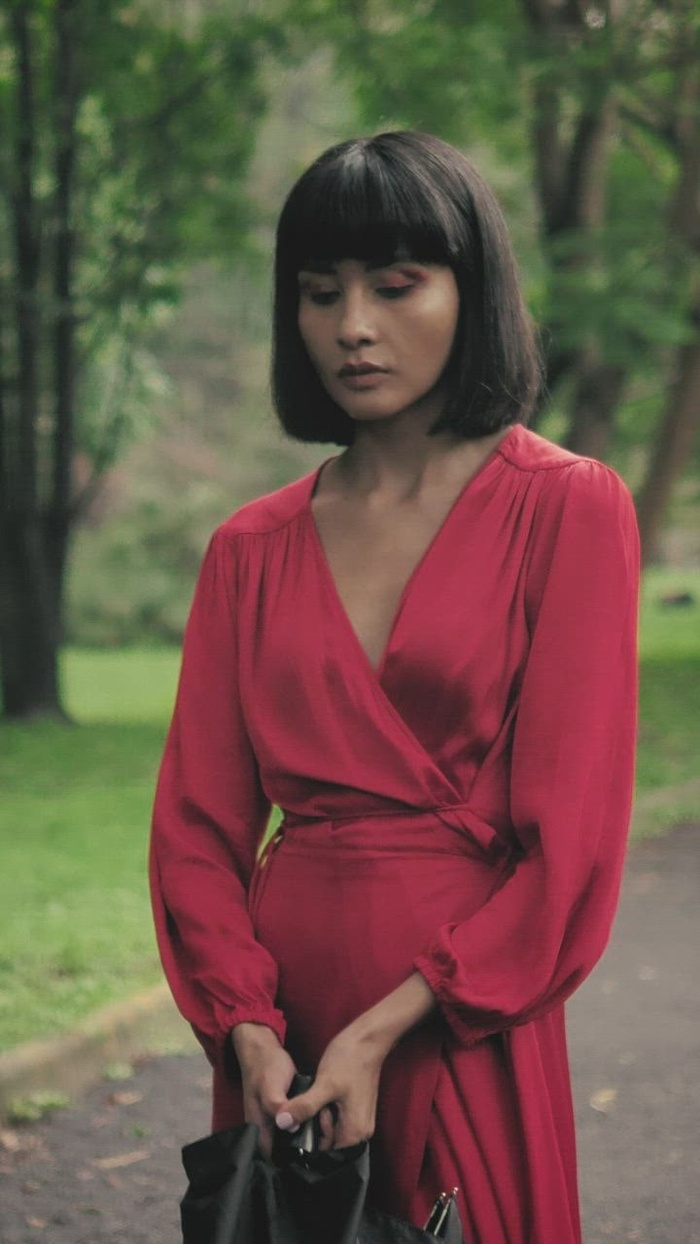 公园里的年轻女人打开她的雨伞来遮雨