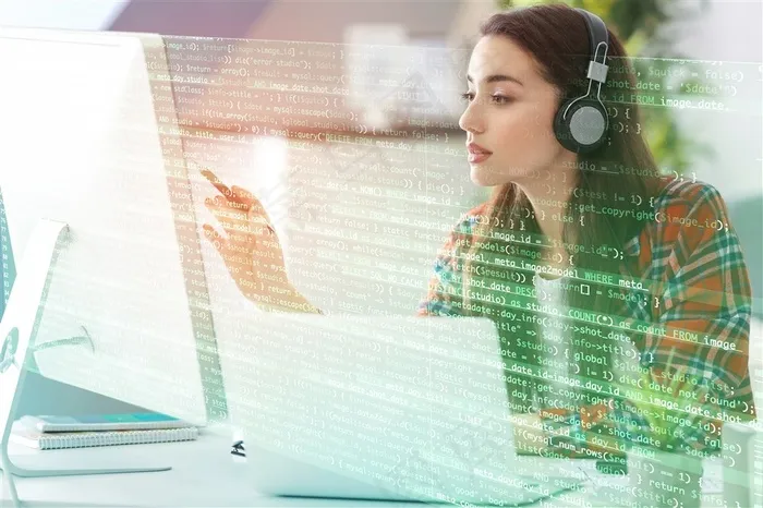 戴着耳麦手指着电脑屏幕的女程序员高清图片