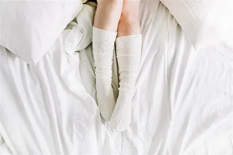 白色床单上穿白色袜子的女生