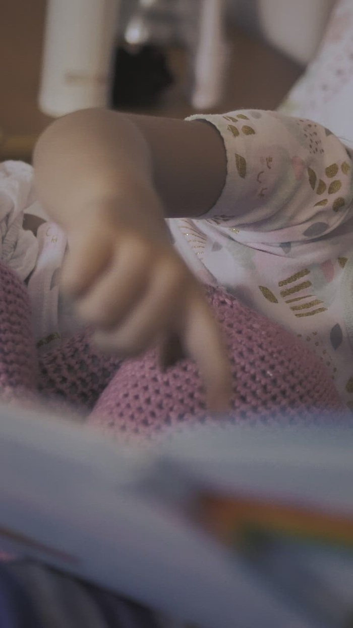 躺在妈妈旁边的小女孩饶有兴趣地看故事书