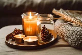 秋冬房间茶几托盘里点燃的香薰杯蜡烛松果玻璃瓶摄影图