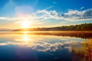 阳光明媚的一天，夏天的早晨，平静的湖面太阳落在平静的湖面上摄影图