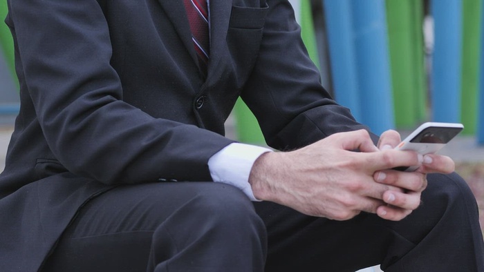 穿西装、戴着面具的男人检查手机