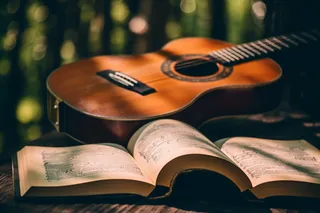 公园里长椅放着打开的书籍和吉他摄影图