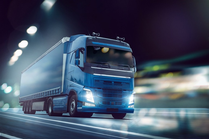 夜色下的公路上行驶的蓝色大货车