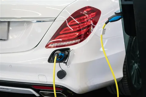 白色汽车尾部正在充电的充电枪高清图片