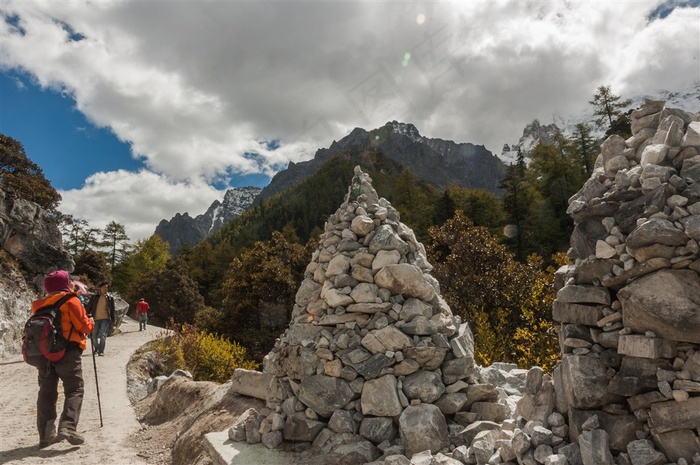 旅行者徒步行走稻城亚丁山路边的玛尼石