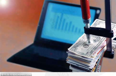 电脑旁的成叠货币背景大图