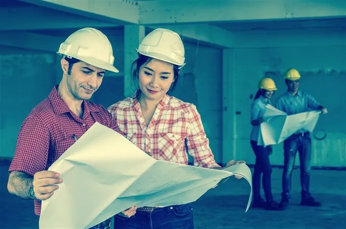 站在毛胚房建筑物中看图纸的设计师高清图片
