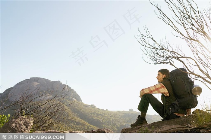 户外探险露营生活-坐在坡地上背着背包的外国男人