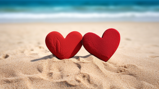 海边沙滩上摆放着两个红色爱心互相依靠摄影图