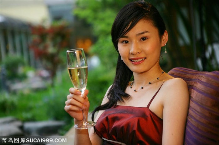 穿着晚礼服端着香槟的女性