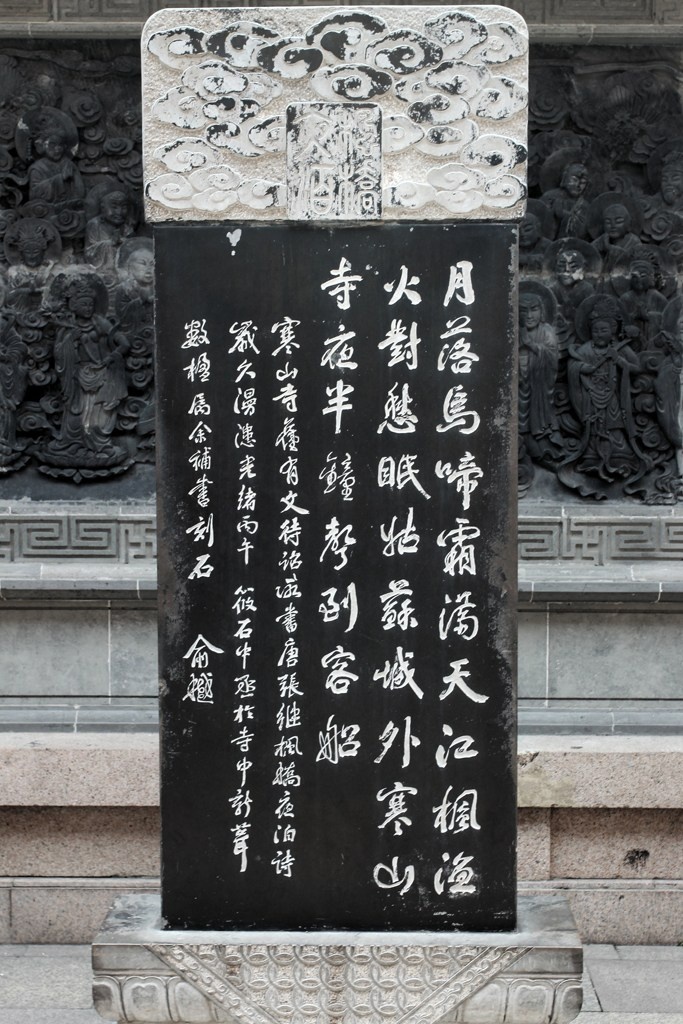 刻满佛像的墙壁前的石碑