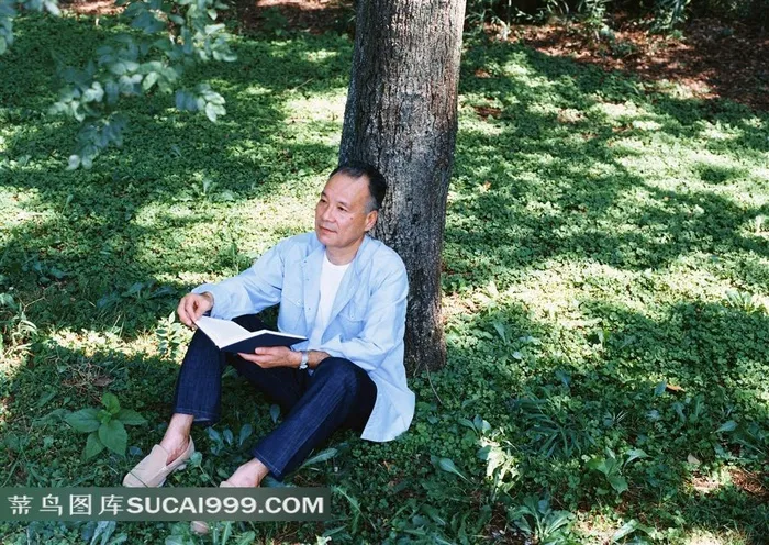 靠树木坐着看书的男老人摄影
