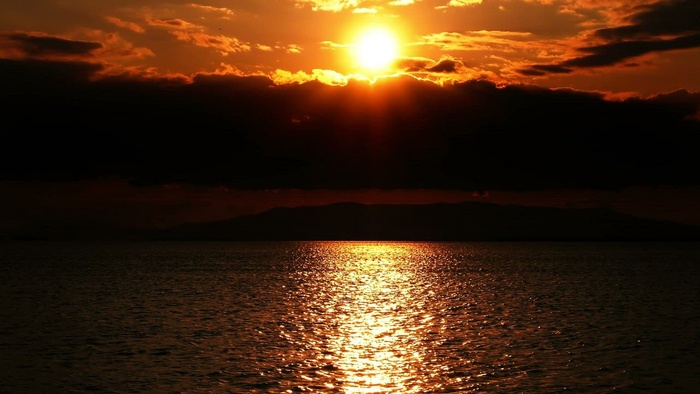 在天空的剪影和  的反射之间的红色日落