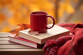 秋冬公园长椅堆放的书籍红色咖啡杯和红色针织围巾摄影图