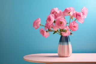 蓝色背景的粉色桌子上的花瓶里的粉色鲜花摄影图