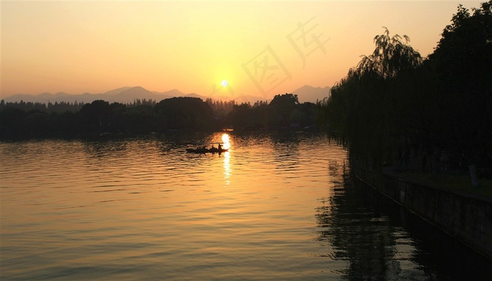 夕阳下湖泊中的手划船摄影图片