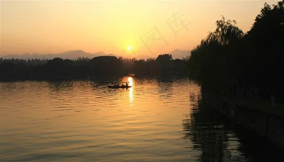 夕阳下湖泊中的手划船摄影图片