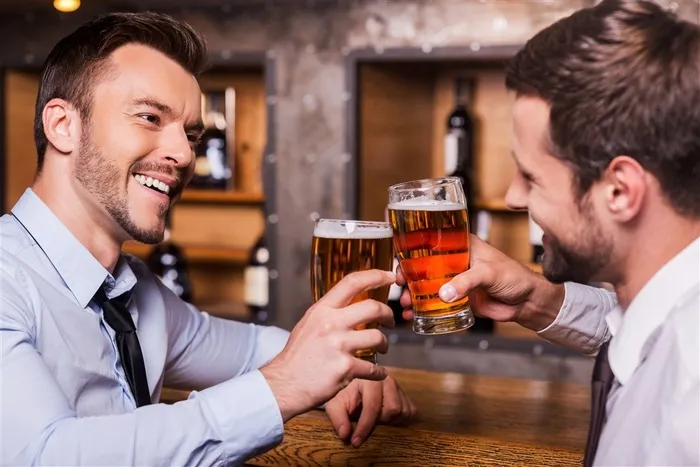 端着啤酒杯微笑碰杯的商务人士高清图片