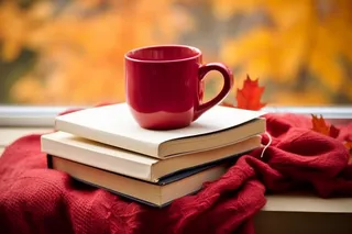 秋冬公园长椅堆放的书籍红色咖啡杯和红色针织围巾摄影图