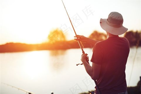 夕阳下站在湖边钓鱼的男士高清图片