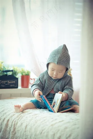 在床上翻看相册的可爱幼儿