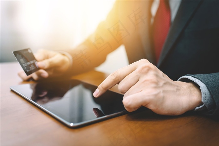 拿着信用卡在平板电脑上操作的商务人士高清图片