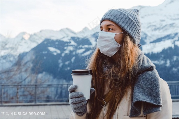 拿着咖啡杯戴口罩看雪山图片