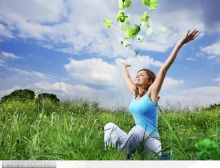 坐在草地上伸展双臂的美女