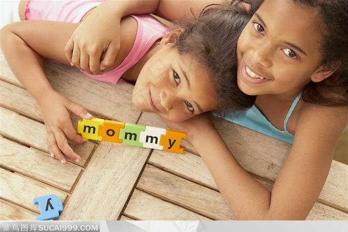 幸福家庭-黑皮肤卷发姊妹两趴在地上玩拼图玩具