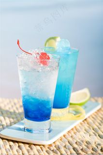 阳光海边竹垫上的蓝色冰镇水果柠檬鸡尾酒果汁