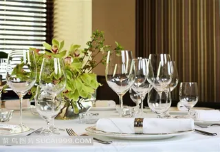 餐桌上的餐具玻璃杯和兰花高清摄影图