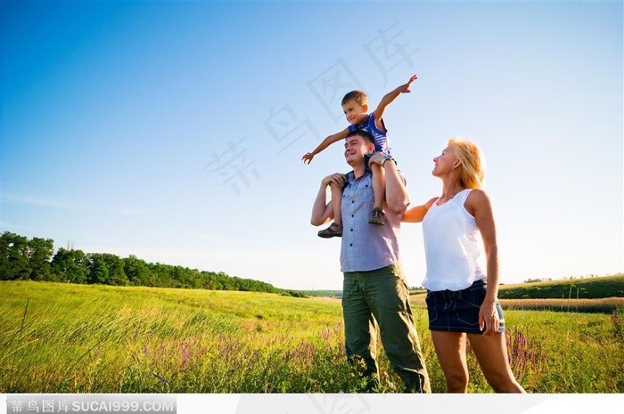 站在郊外草地上的一家三口